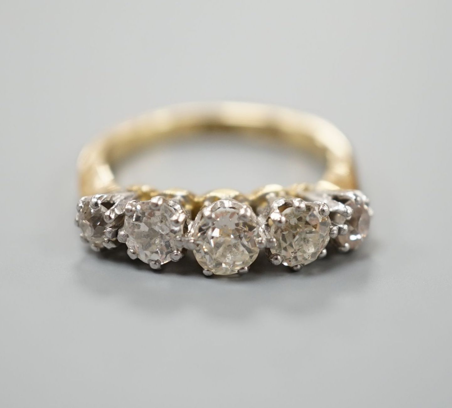 An 18ct and graduated five stone diamond set half hoop ring, size K, gross weight 4 grams.